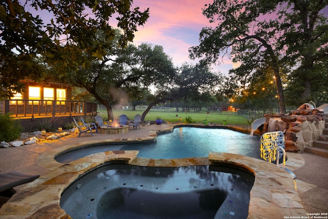 1162 Thunder Cloud, Spring Branch, TX 78070 - pool at dusk featuring a fire pit, a patio area, a pool with connected hot tub, and a lawn