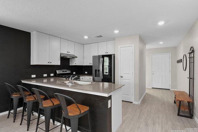 6041 Vestige Bnd, Bulverde, TX 78163 - kitchen with stainless steel appliances, a peninsula, light wood-style floors, white cabinetry, and recessed lighting