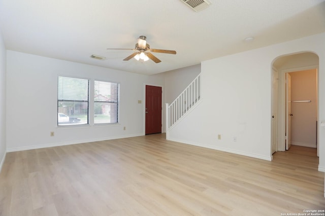 5510 Camry Spgs, San Antonio, TX 78251 - unfurnished living room featuring a ceiling fan, arched walkways, light wood-style floors, and stairs