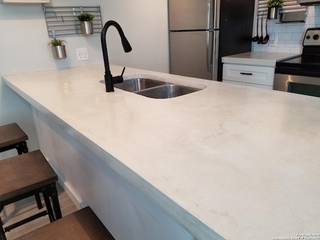 908 Camaron St, San Antonio, TX 78212 - kitchen featuring appliances with stainless steel finishes, backsplash, white cabinets, light countertops, and a breakfast bar