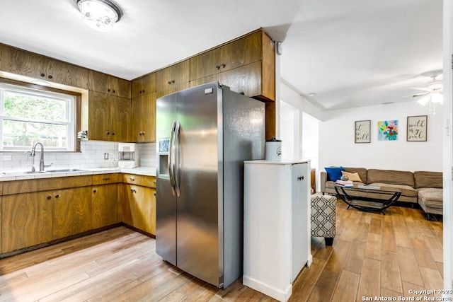 3035 Sir Phillip, San Antonio, TX 78209 - kitchen featuring stainless steel fridge, light wood finished floors, a ceiling fan, tasteful backsplash, and tile counters