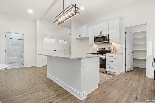 149 Camino Verde Ln, Vernia, TX 78121 - kitchen with stainless steel appliances, white cabinets, light wood finished floors, light stone counters, and backsplash