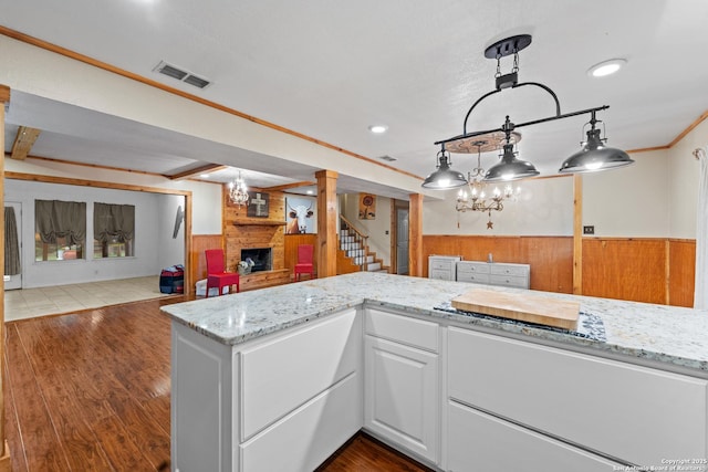 6033 Cammie, Leon Valley, TX 78238 - kitchen featuring wooden walls, a large fireplace, open floor plan, light stone counters, and white cabinetry