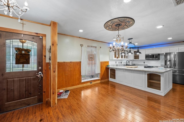 6033 Cammie, Leon Valley, TX 78238 - kitchen with stainless steel appliances, a chandelier, white cabinets, glass insert cabinets, and wainscoting