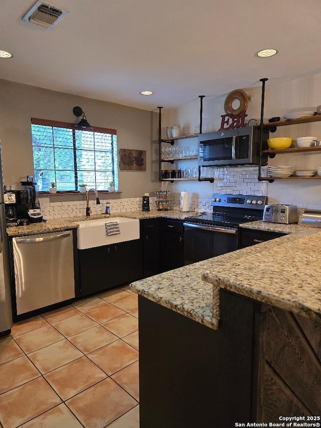 405 Short Circuit Unit 1, Horseshoe Bay, TX 78657 - kitchen featuring appliances with stainless steel finishes, open shelves, decorative backsplash, light tile patterned flooring, and light stone counters