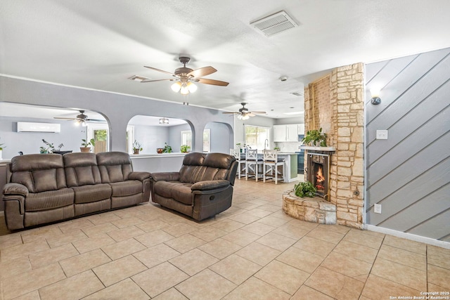 3702 Pipers Fld, San Antonio, TX 78251 - living area with ceiling fan, a wall mounted AC, light tile patterned flooring, and a stone fireplace