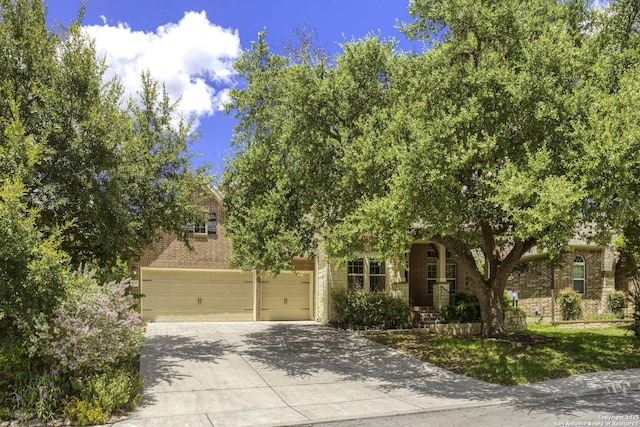 10657 Foxen Way, Helotes, TX 78023 - view of property hidden behind natural elements featuring brick siding, concrete driveway, and an attached garage