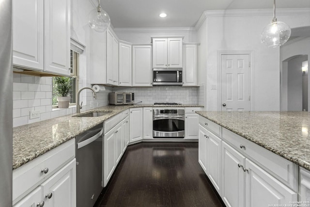 10657 Foxen Way, Helotes, TX 78023 - kitchen featuring appliances with stainless steel finishes, arched walkways, white cabinetry, dark wood finished floors, and light stone countertops