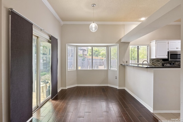 4242 Shady Tree Ln, San Antonio, TX 78247 - kitchen featuring stainless steel microwave, white cabinetry, dark wood-type flooring, crown molding, and dark countertops