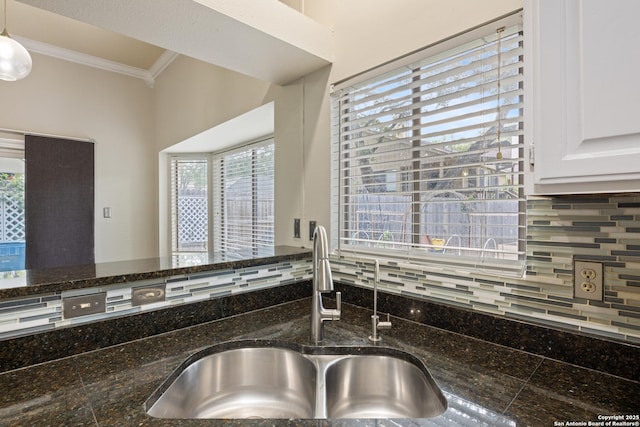 4242 Shady Tree Ln, San Antonio, TX 78247 - kitchen featuring crown molding, backsplash, dark stone counters, white cabinetry, and decorative light fixtures