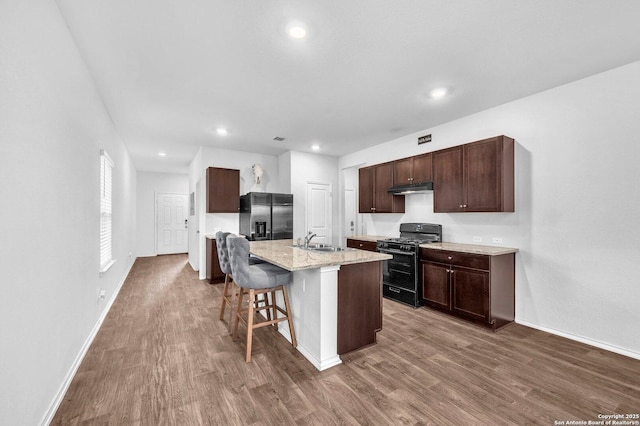 14016 Breccia Loop, San Antonio, TX 78253 - kitchen featuring black range with gas cooktop, refrigerator with ice dispenser, under cabinet range hood, dark wood finished floors, and dark brown cabinetry