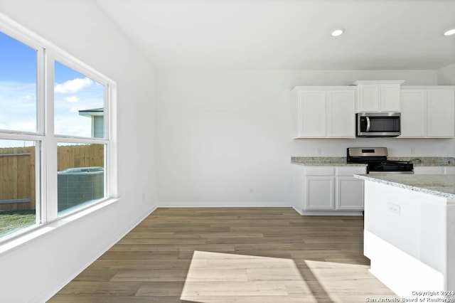 10950 Lafayette Loop, San Antonio, TX 78109 - kitchen featuring appliances with stainless steel finishes, white cabinetry, light wood-type flooring, light stone countertops, and recessed lighting