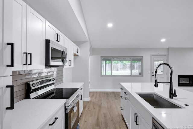 5807 Sun Rdg, San Antonio, TX 78247 - kitchen with appliances with stainless steel finishes, light stone countertops, decorative backsplash, white cabinets, and light wood-style flooring