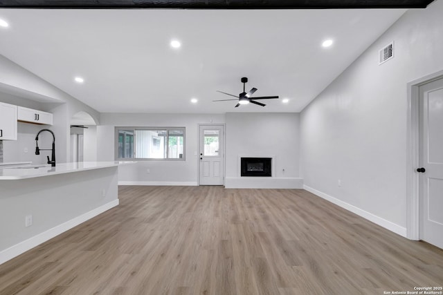 5807 Sun Rdg, San Antonio, TX 78247 - unfurnished living room featuring ceiling fan, light wood-style floors, a glass covered fireplace, recessed lighting, and arched walkways
