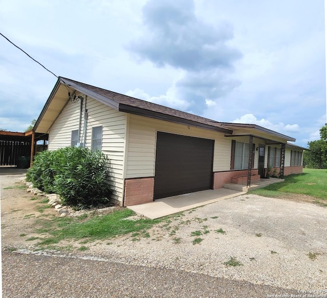403 E Meyer, Falls City, TX 78113 - view of side of home featuring a garage, asphalt driveway, and brick siding