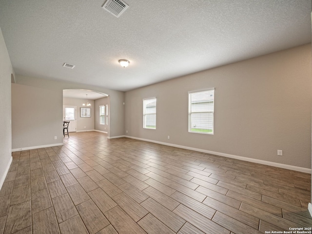 754 Farmers Dell, New Braunfels, TX 78130 - unfurnished living room with arched walkways, wood tiled floors, a textured ceiling, and a chandelier