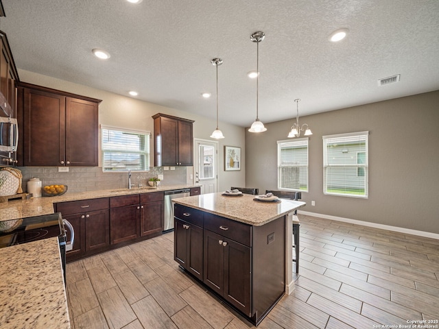 754 Farmers Dell, New Braunfels, TX 78130 - kitchen with dishwasher, backsplash, a kitchen island, wood finish floors, and a textured ceiling