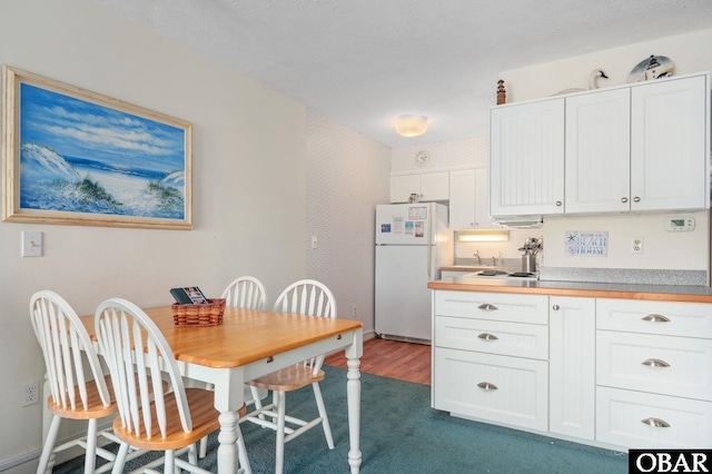 117 Sea Colony Dr Unit 211B, Duck, NC 27949 - kitchen featuring dark carpet, freestanding refrigerator, white cabinetry, and light countertops
