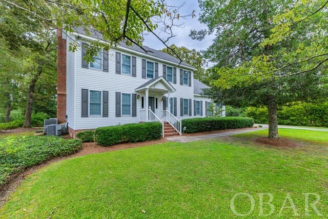 colonial house featuring central AC, a chimney, and a front lawn