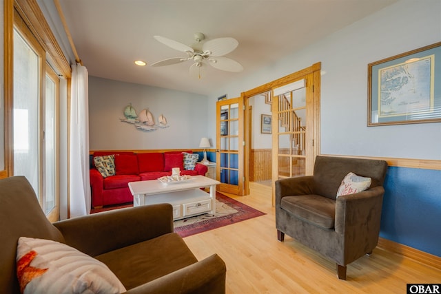 living area with a ceiling fan, wood finished floors, a wainscoted wall, recessed lighting, and french doors