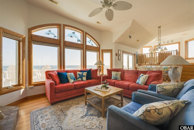 living room with visible vents, light wood-style flooring, ceiling fan with notable chandelier, baseboards, and lofted ceiling