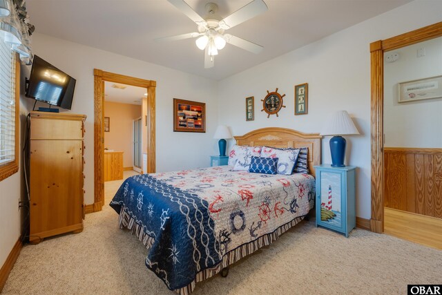 carpeted bedroom featuring wainscoting and a ceiling fan