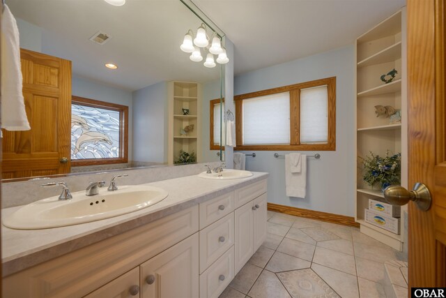 bathroom featuring a sink, visible vents, double vanity, and tile patterned floors