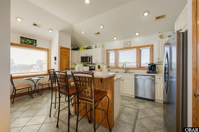 kitchen featuring a kitchen bar, visible vents, a sink, stainless steel appliances, and light countertops