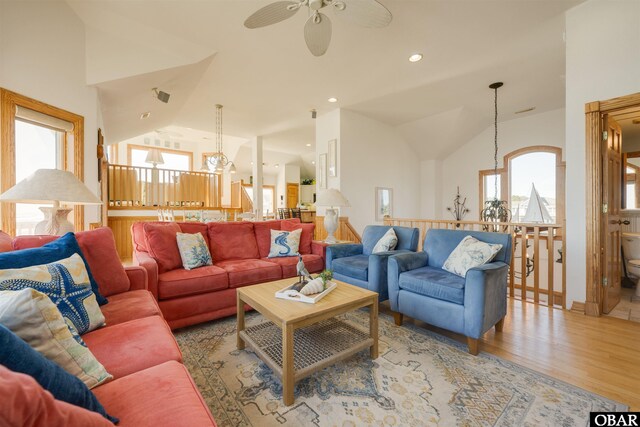 living area with recessed lighting, ceiling fan with notable chandelier, light wood-style floors, and vaulted ceiling