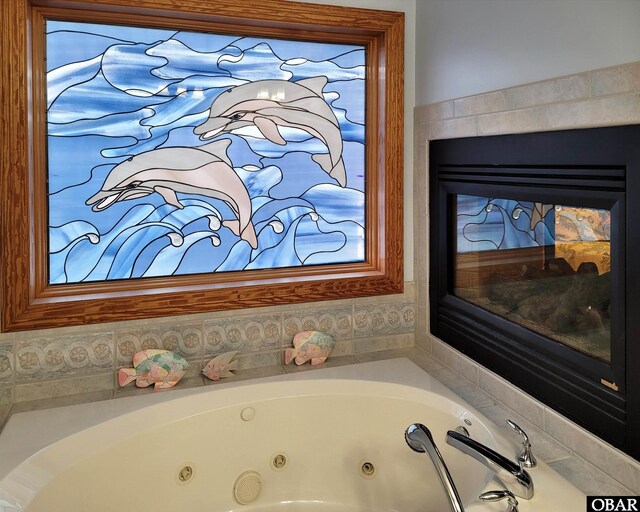 bathroom with a tub with jets and a glass covered fireplace