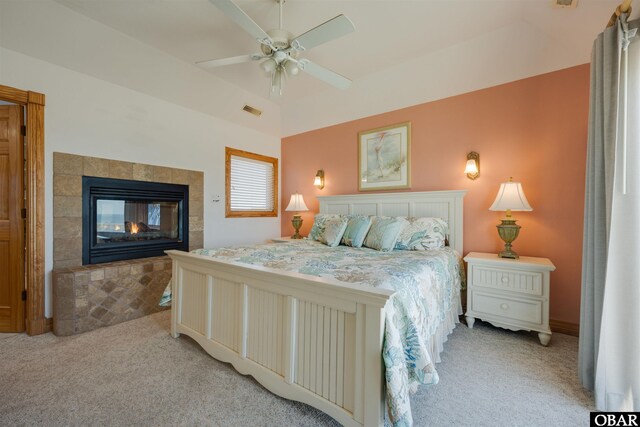 bedroom featuring a tiled fireplace, light colored carpet, visible vents, and ceiling fan