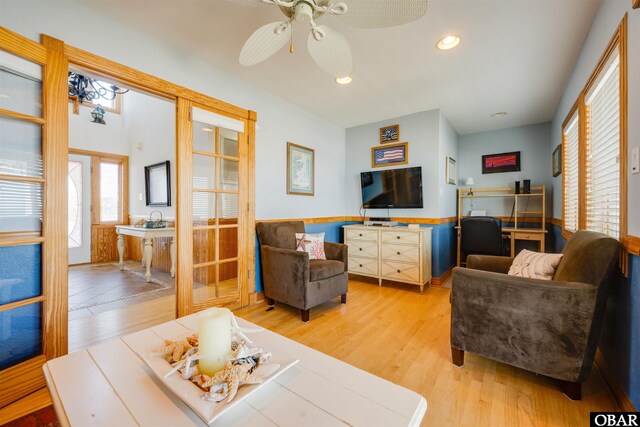 living room with recessed lighting, a wainscoted wall, light wood-style floors, and french doors