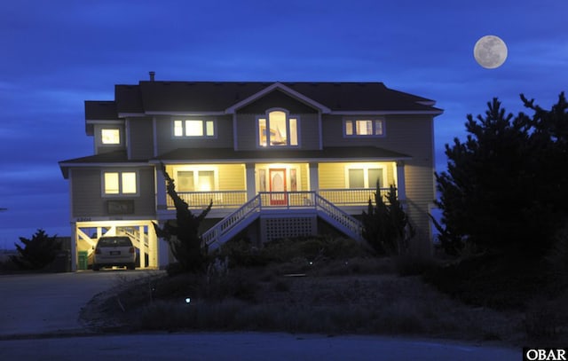 view of front of house featuring stairway, a carport, covered porch, and driveway