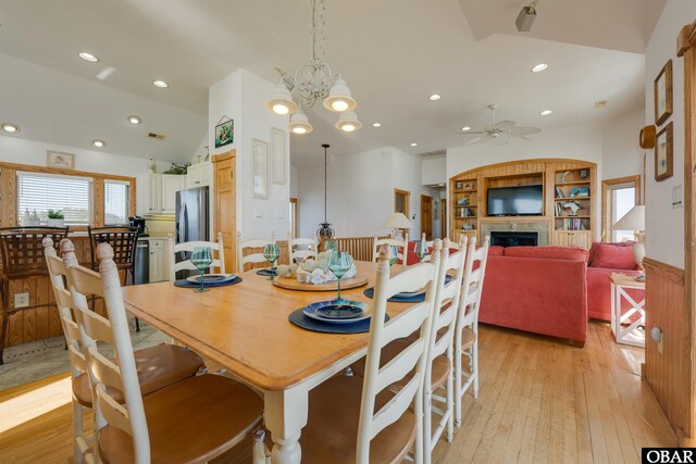 dining space featuring recessed lighting, a fireplace, light wood-type flooring, and vaulted ceiling