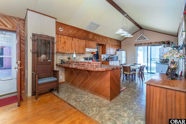 278 Bayview Dr, Stumpy Point, NC 27978 - kitchen featuring under cabinet range hood, brown cabinets, a peninsula, freestanding refrigerator, and stainless steel microwave