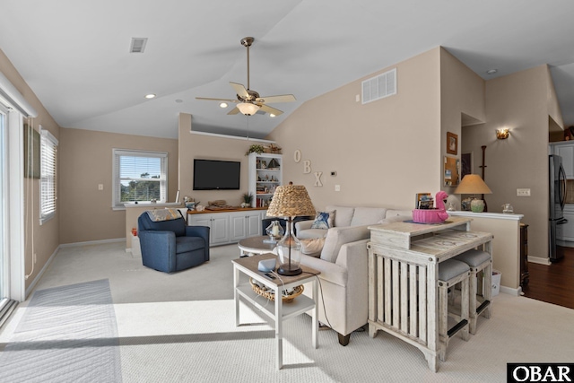 living area featuring light colored carpet, visible vents, vaulted ceiling, and baseboards