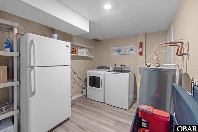 laundry room featuring light wood-type flooring, laundry area, electric water heater, and washer and clothes dryer