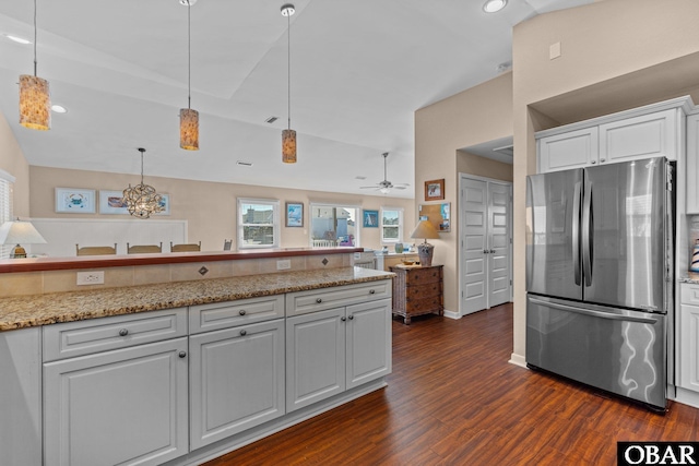 kitchen featuring lofted ceiling, dark wood-style flooring, white cabinets, hanging light fixtures, and freestanding refrigerator