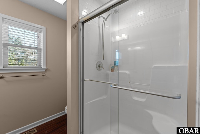 full bathroom featuring wood finished floors, a shower stall, toilet, and baseboards