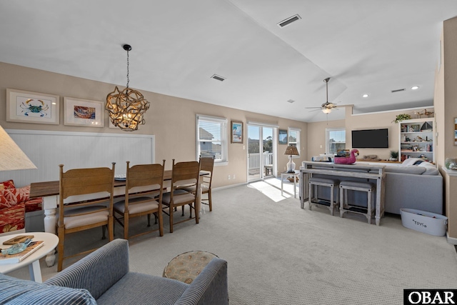 living area featuring light colored carpet, visible vents, vaulted ceiling, and ceiling fan with notable chandelier