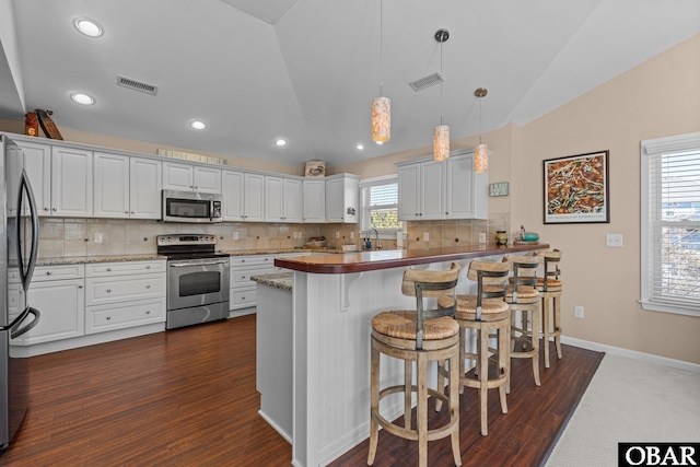 kitchen with vaulted ceiling, stainless steel appliances, backsplash, and visible vents