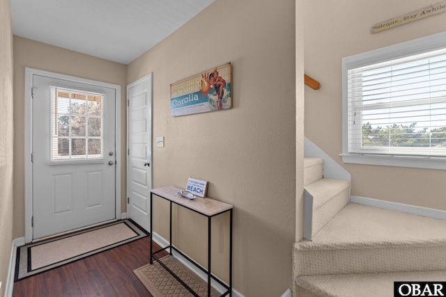 doorway to outside featuring dark wood-style floors, stairs, and baseboards