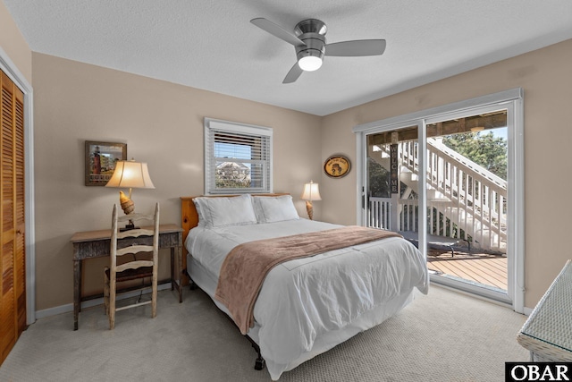 bedroom with light carpet, access to outside, multiple windows, and a textured ceiling