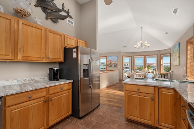 kitchen featuring appliances with stainless steel finishes, visible vents, hanging light fixtures, and light stone countertops