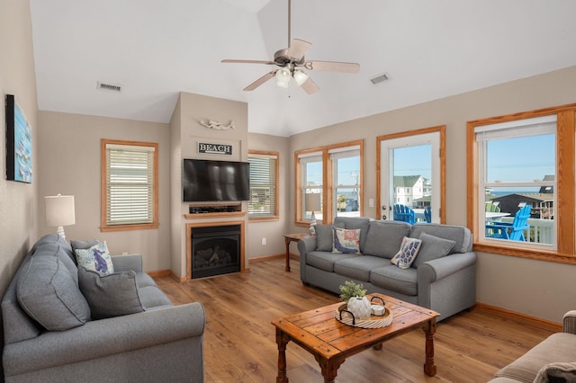 living room featuring lofted ceiling, a healthy amount of sunlight, light wood-type flooring, and visible vents