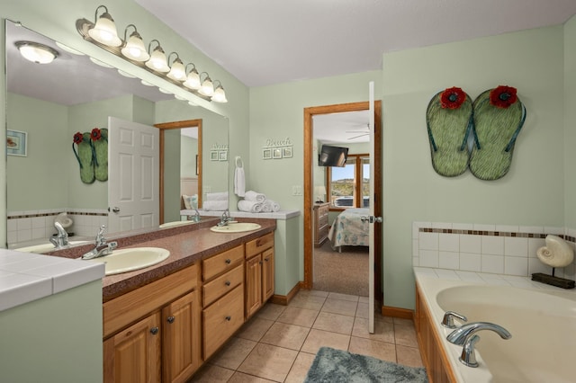 bathroom featuring a sink, double vanity, tile patterned flooring, and ensuite bath