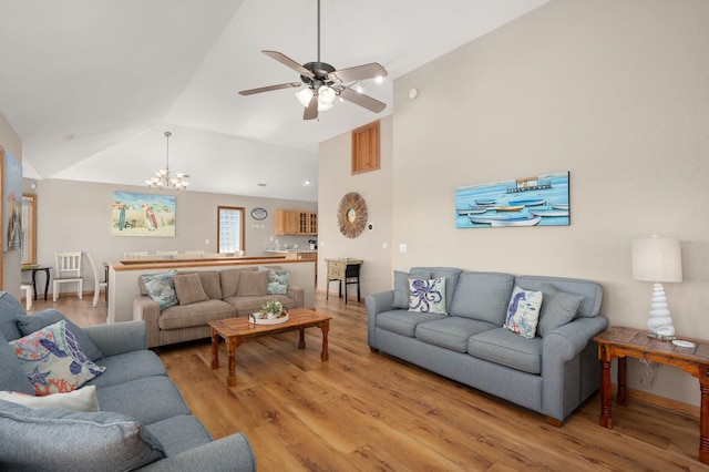 living area with lofted ceiling, ceiling fan with notable chandelier, visible vents, and light wood-style floors