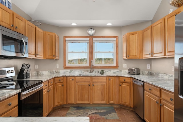 kitchen featuring light stone countertops, vaulted ceiling, stainless steel appliances, and a sink