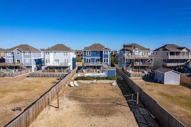 back of house with a residential view, fence, and a storage shed