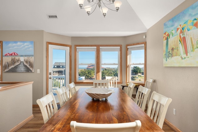 dining space featuring baseboards, wood finished floors, visible vents, and a notable chandelier